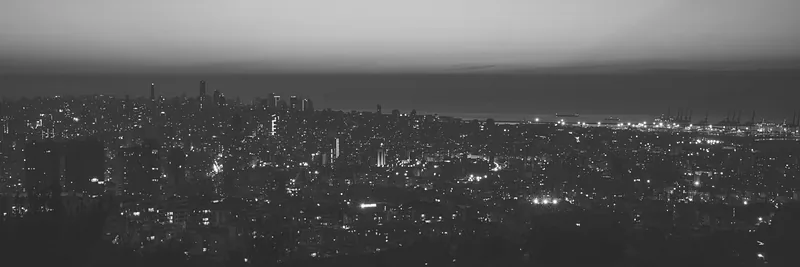 The Beirut skyline at night, seen from the hills above the city, with the sea and the port in the distance